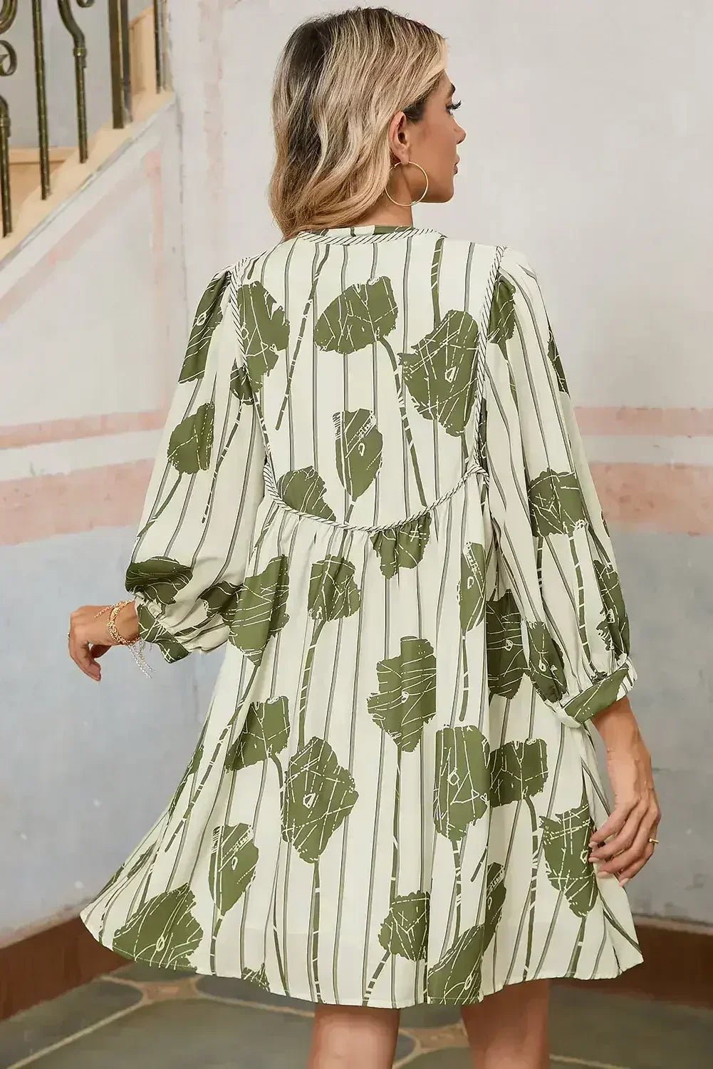 Woman wearing a green and white patterned dress in an indoor setting.