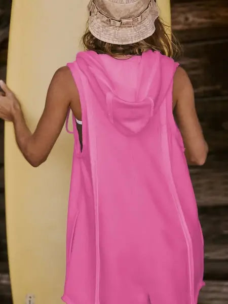 Person wearing a pink sleeveless hoodie with a hood, holding a yellow surfboard.