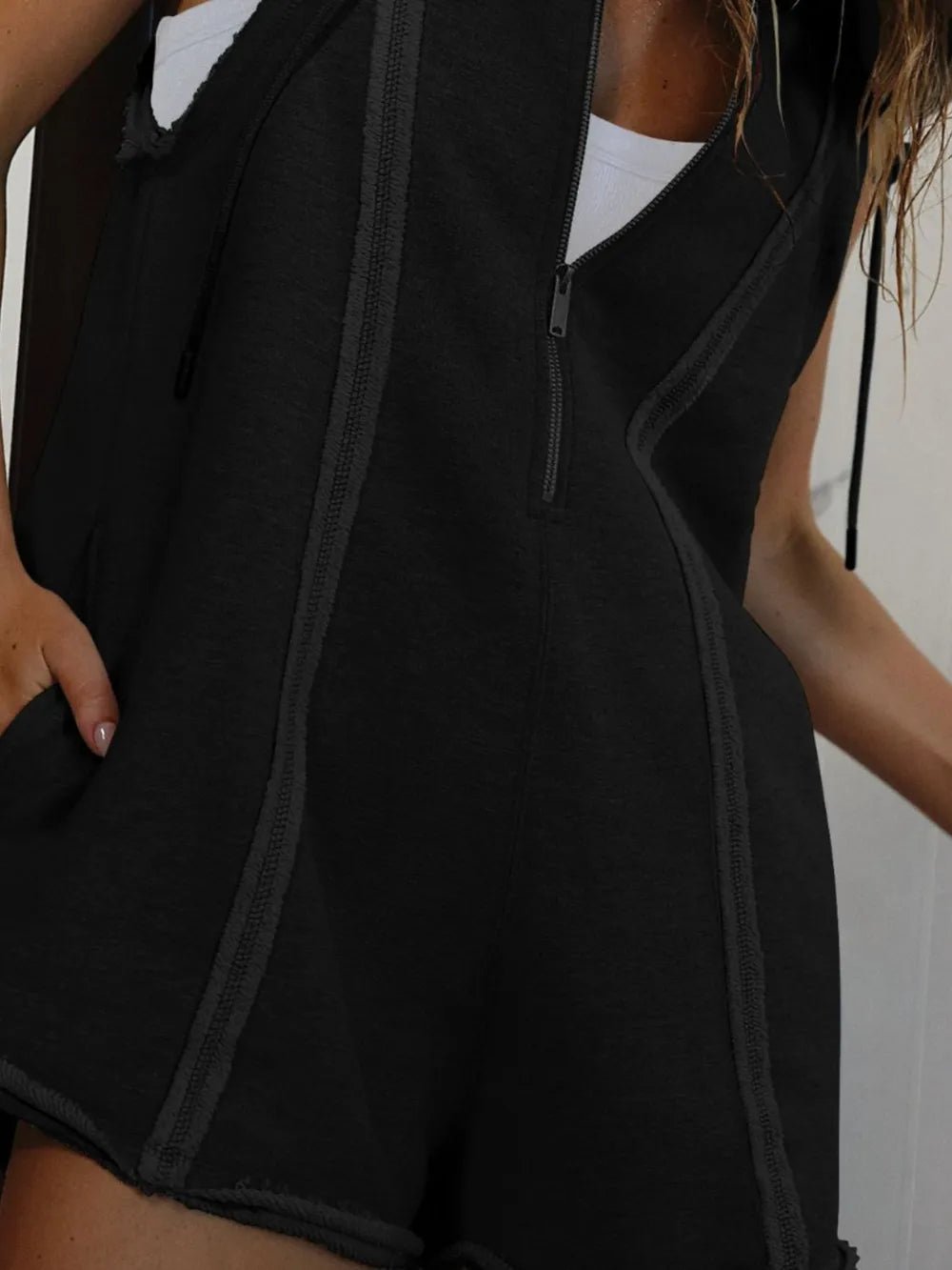 Person wearing a black sleeveless top with a zipper detail.