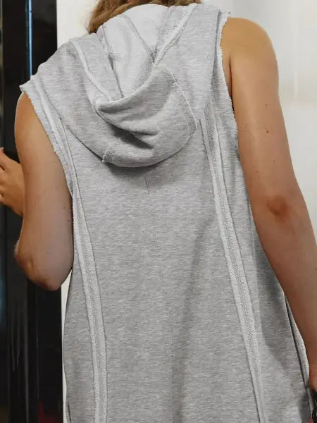 Person wearing a sleeveless gray hoodie with a hood.