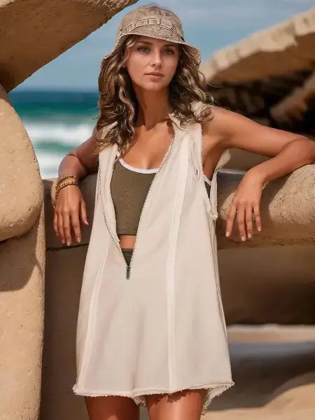 Woman in a white cover-up and green top leaning against a wooden structure outdoors.