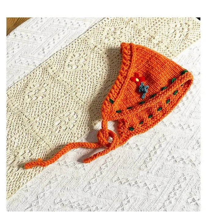 Orange boho style crochet headband with braided ties and floral embroidery on white fabric
