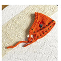 Orange boho style crochet headband with braided ties and floral embroidery on white fabric