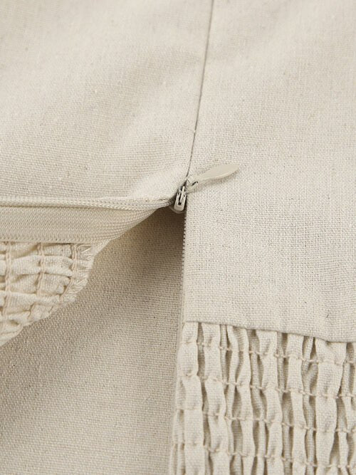 Close-up of a beige textured fabric with a zipper detail.