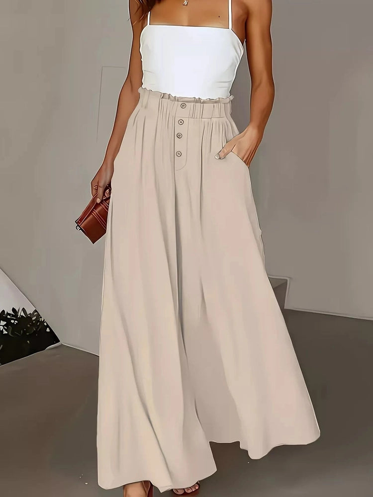 Woman wearing a white top and beige skirt with a brown clutch against a neutral background