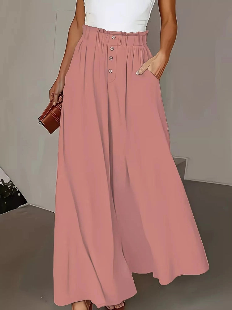 Person wearing a long pink wide leg pants with a plain background