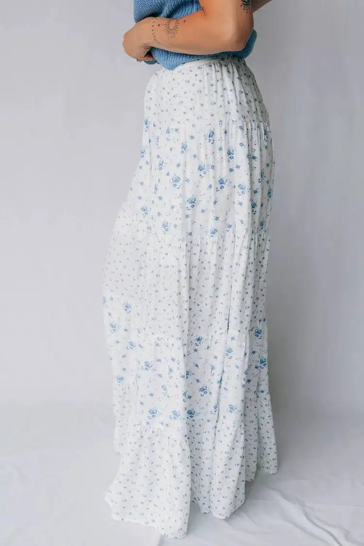 Person wearing white floral pants against a plain background arms crossed