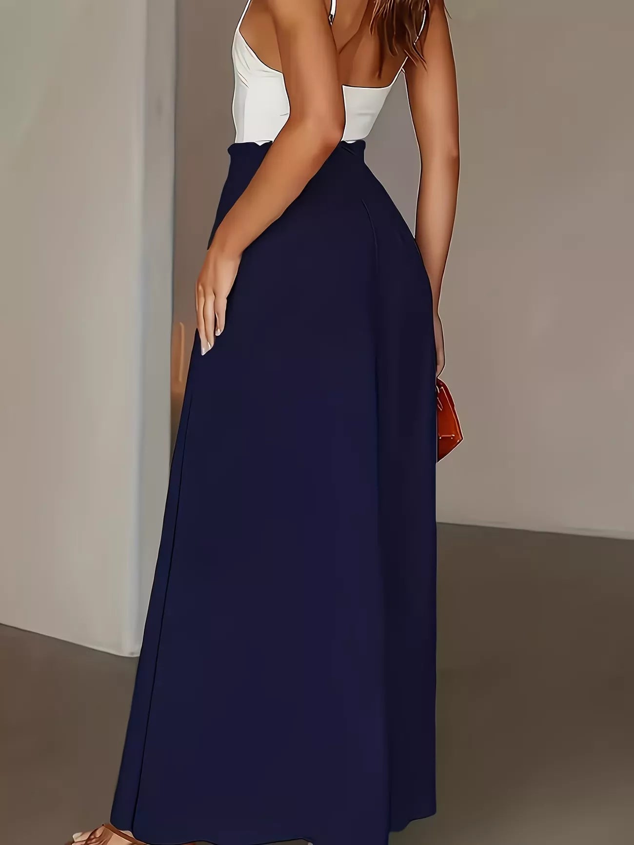 Person wearing a white top and navy blue skirt against a neutral background