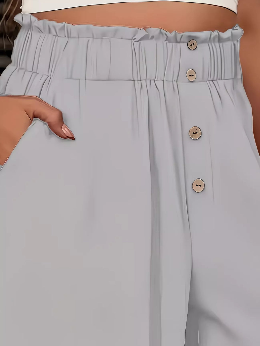 Light gray pants with button details worn by a person.