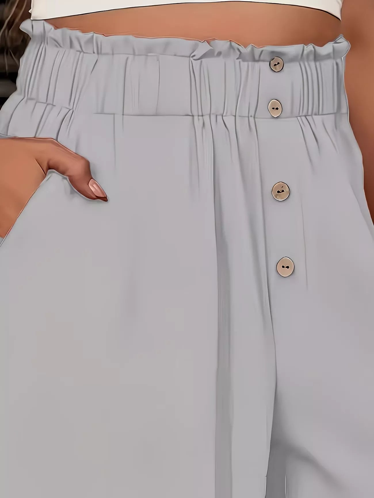 Light gray pants with button details worn by a person.