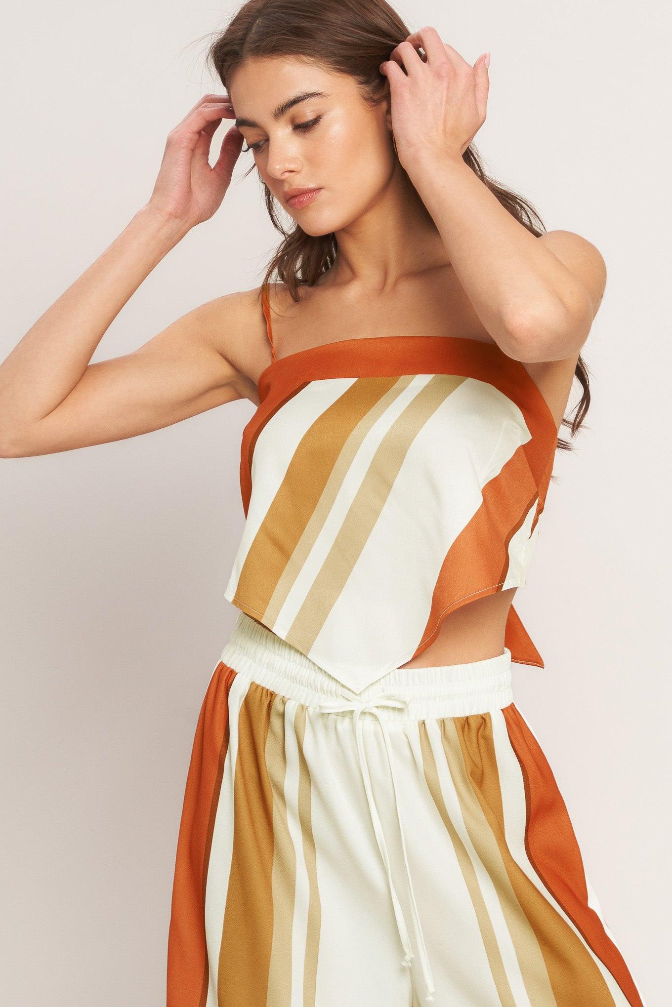 Woman wearing a striped dress with orange, white, and beige colors on a plain background