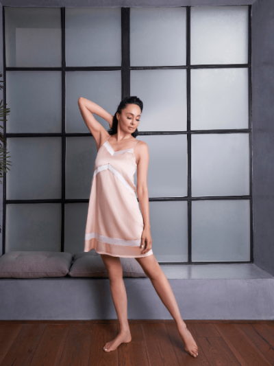 Woman in a light pink dress standing in a room with a modern design.