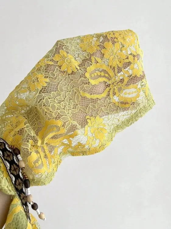 Close up of sheer yellow green floral lace fabric and beaded trim