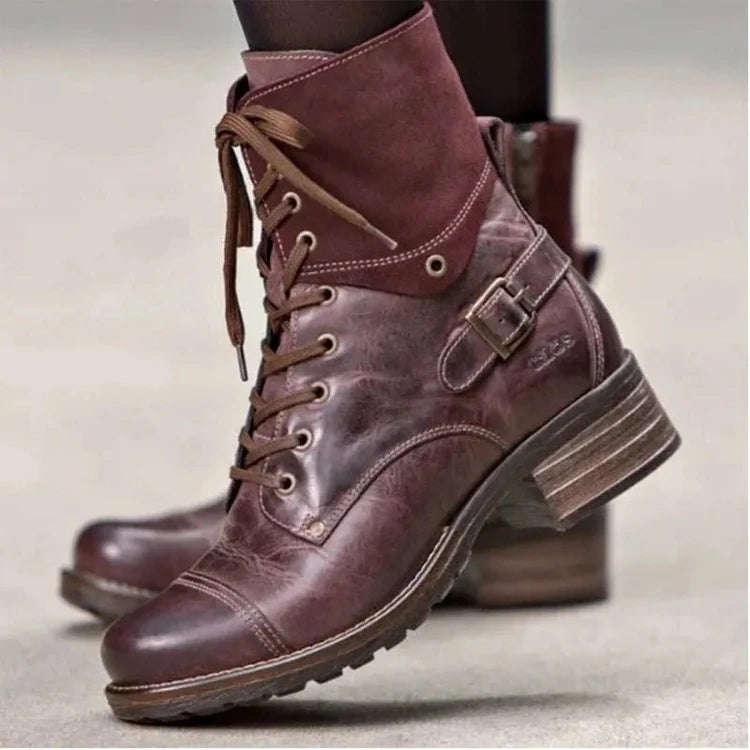 Brown leather boots with buckles on a neutral background