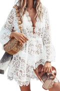 Woman wearing a white lace dress holding a woven handbag and sandals.