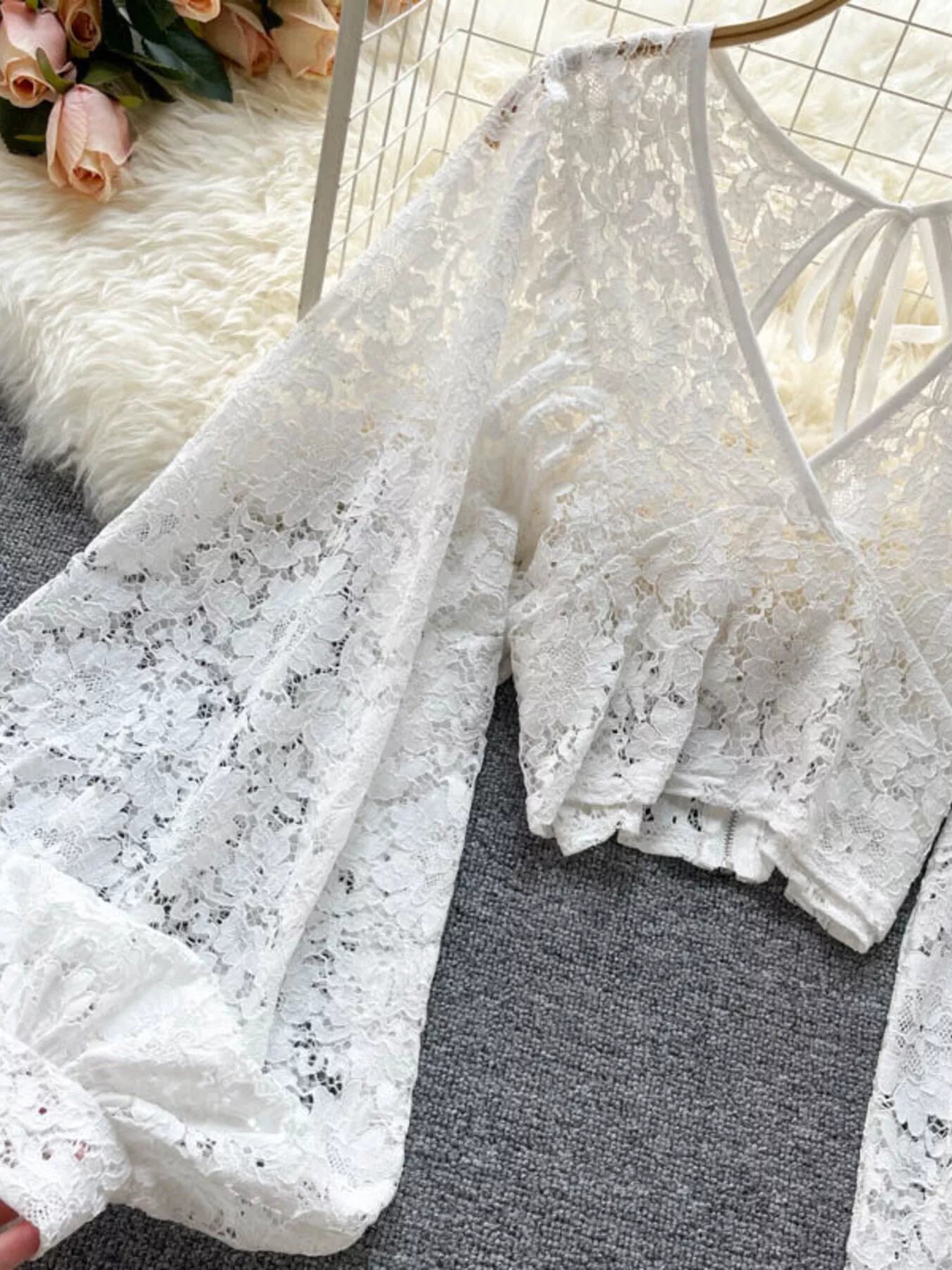 White lace fabric on a textured surface with flowers in the background