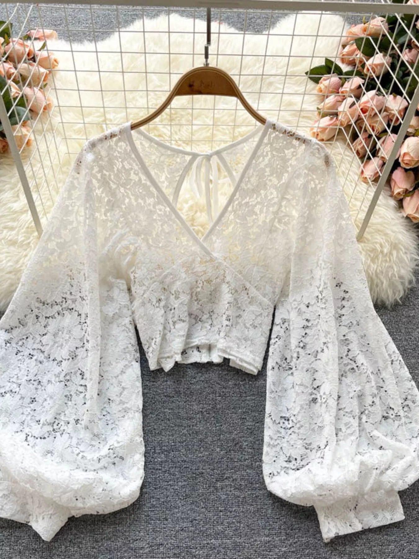 White lace top on a hanger with floral decorations in the background
