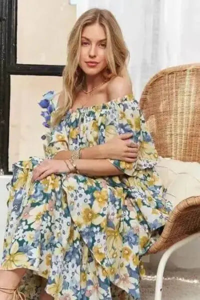 Woman in a floral dress sitting on a wicker chair.