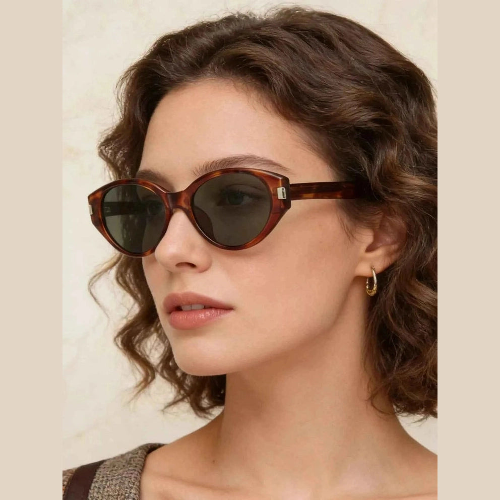 Woman wearing tortoiseshell cat-eye sunglasses with green-tinted lenses in profile
