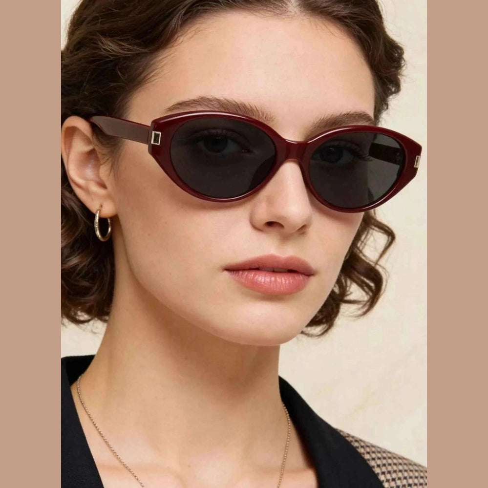 Close-up of burgundy acetate cat-eye sunglasses on woman with gold hoop earrings