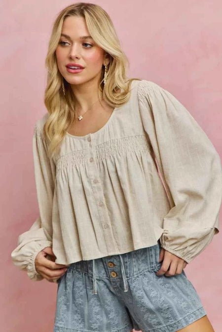 Woman wearing a beige blouse and denim shorts against a pink background