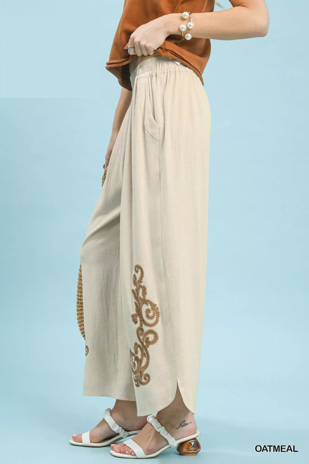 Beige pants with gold embroidery on a light blue background
