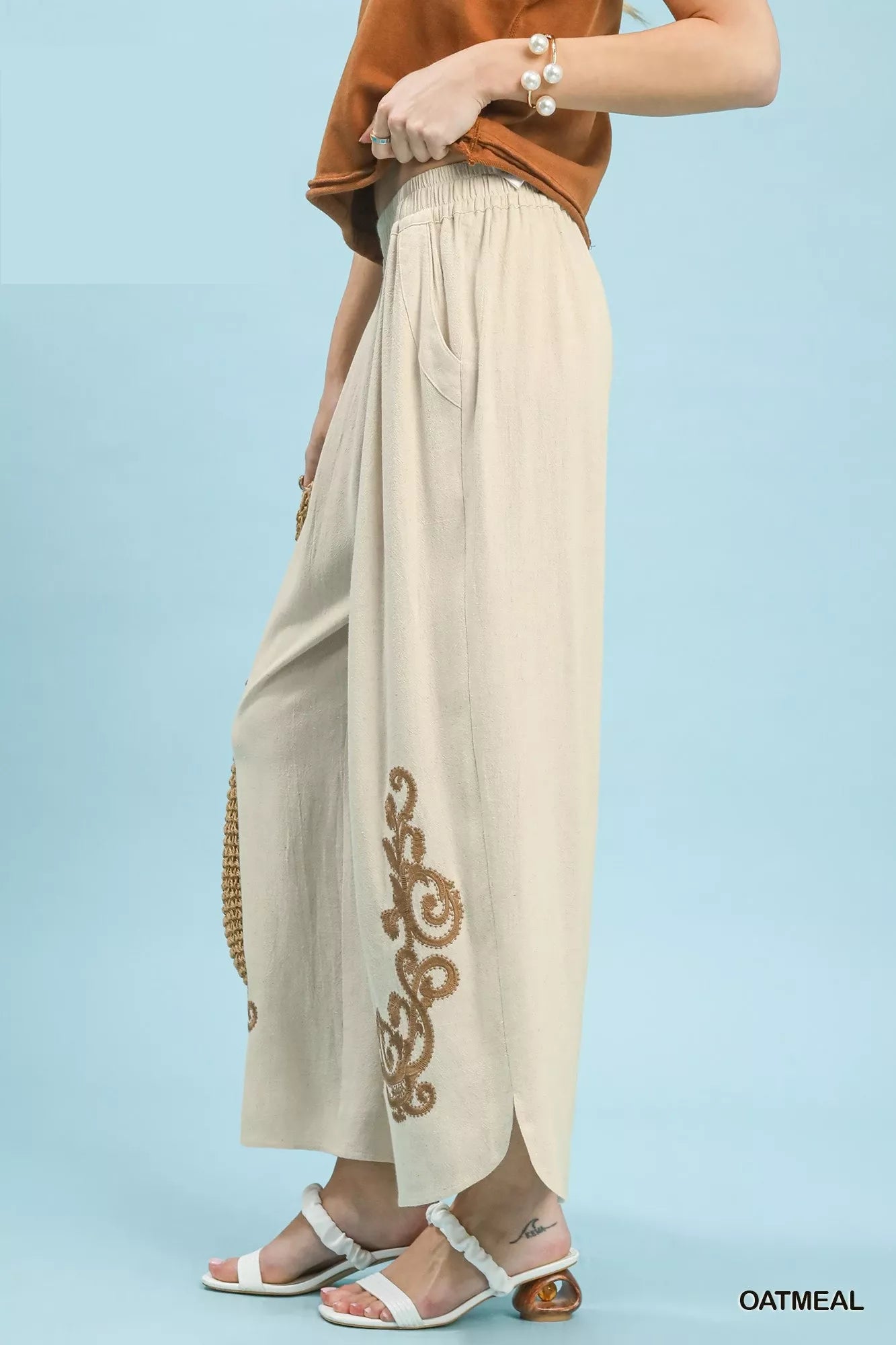 Beige pants with gold embroidery on a light blue background
