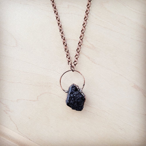 Necklace with a dark stone pendant on a light wooden surface