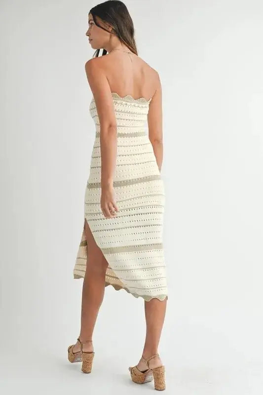 Woman wearing a strapless, crocheted dress with a white background