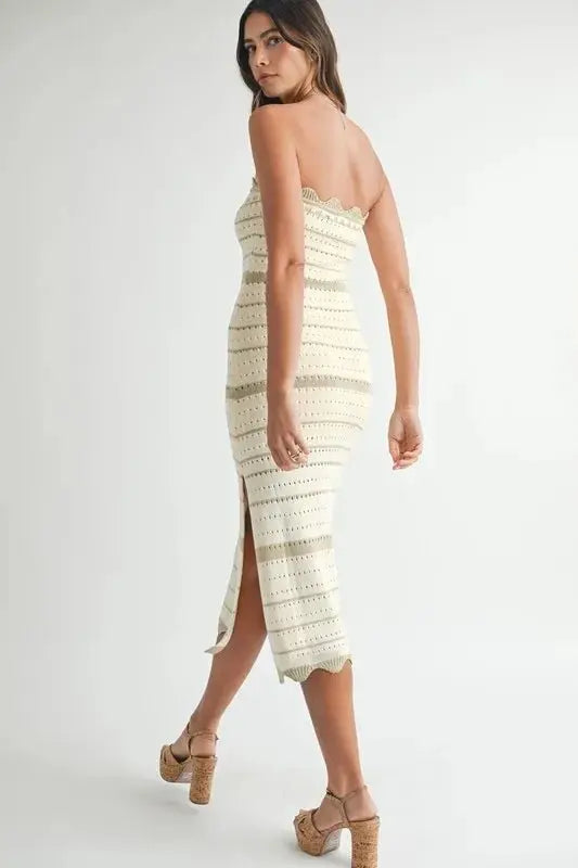 Woman wearing a strapless, crocheted dress with a white background