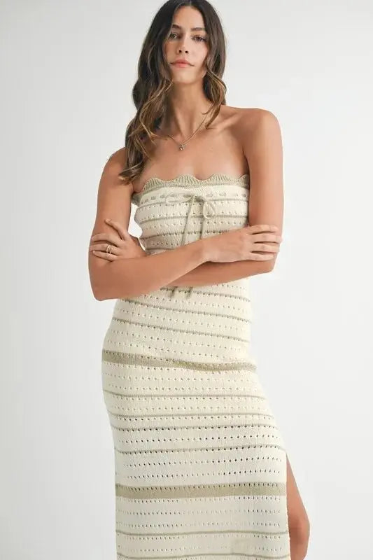 Woman wearing a strapless, crocheted dress with a white background