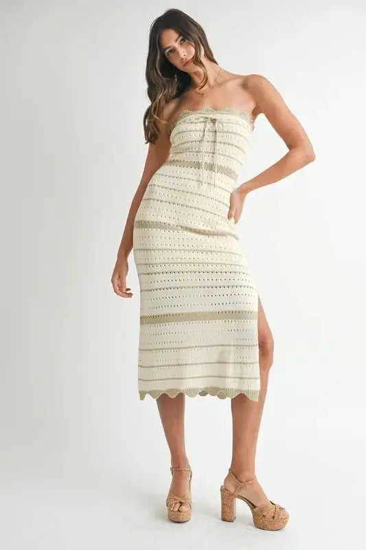 Woman wearing a strapless, crocheted dress with a white background