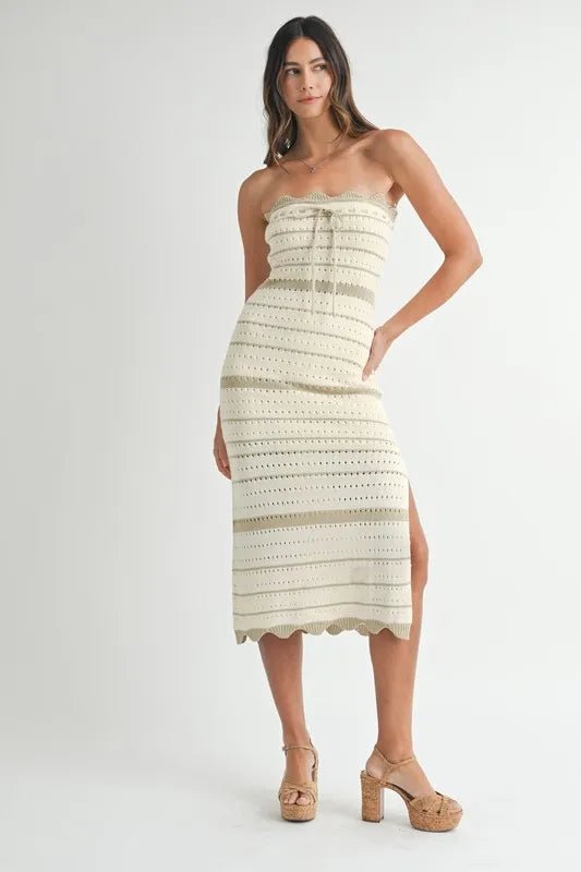 Woman wearing a strapless, crocheted dress with a white background