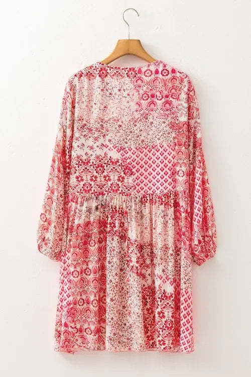Red and white patterned dress on a wooden hanger against a white background