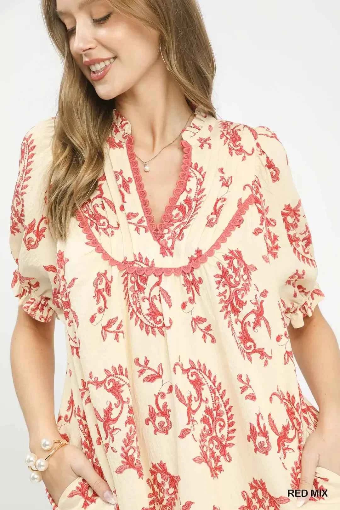Woman wearing a cream and red patterned dress on a white background