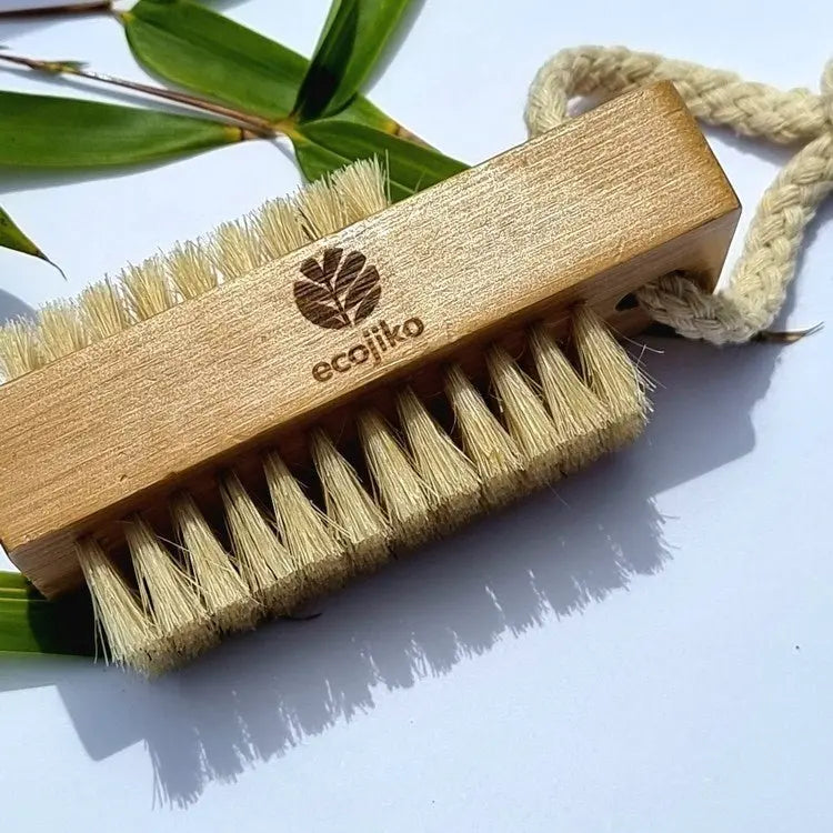Close-up of rectangular wooden nail brush with plant-based bristles and engraved logo