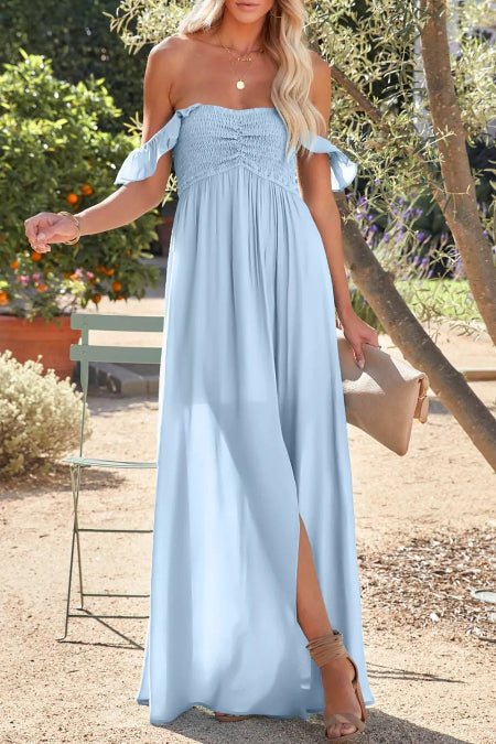 Woman wearing a light blue dress with a slit, standing outdoors.