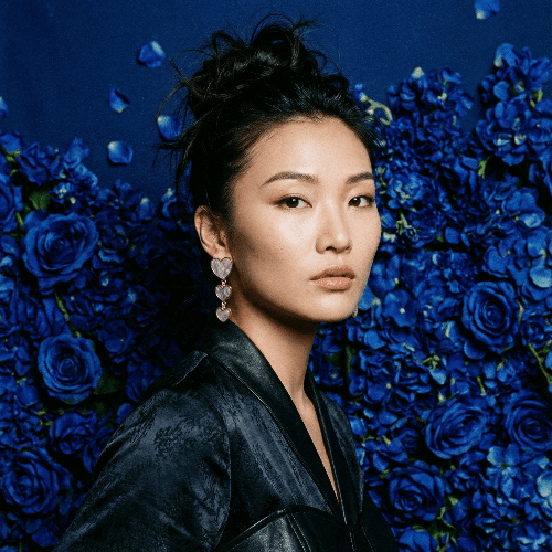 Woman in a black outfit standing against a blue floral background