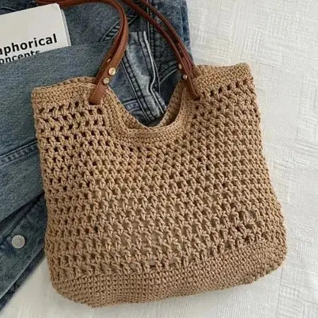 Brown crochet bag with brown handle on denim jeans against a light background