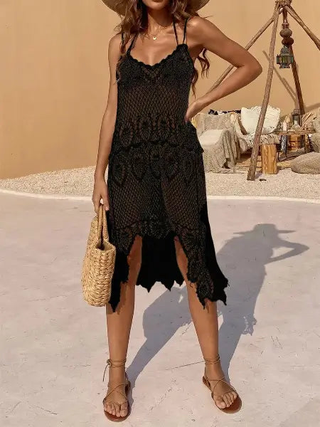 Woman wearing a black crochet dress with a straw bag in a desert-like setting
