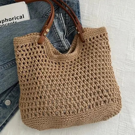 Brown crochet bag with brown handle on denim jeans against a light background