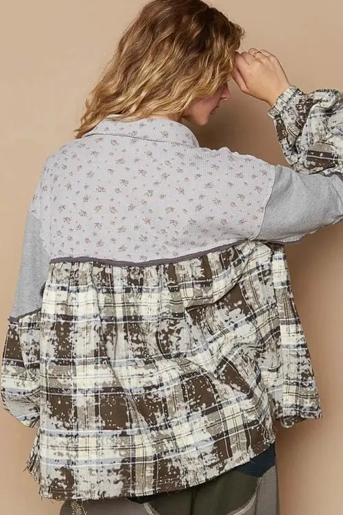 Woman wearing a patterned shirt, teal top, gray pants, and sneakers against a beige background