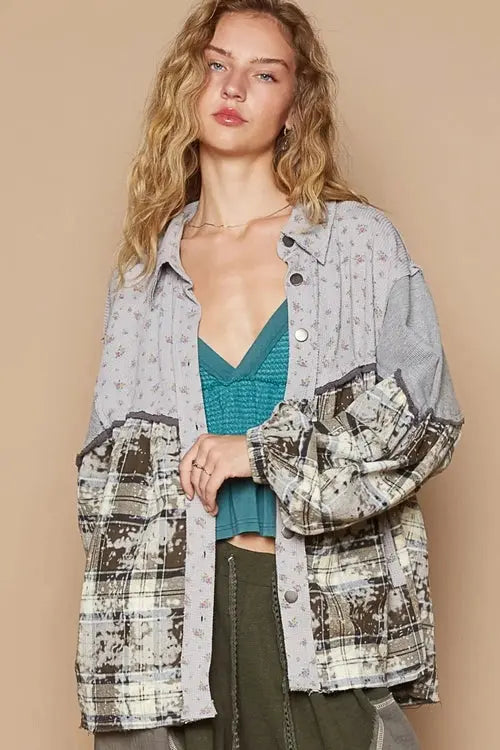 Woman wearing a patterned shirt, teal top, gray pants, and sneakers against a beige background