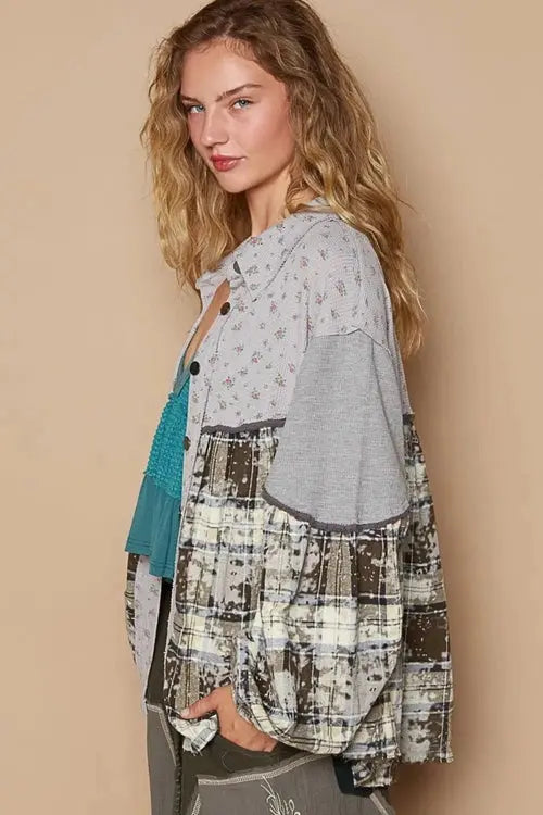 Woman wearing a patterned shirt, teal top, gray pants, and sneakers against a beige background