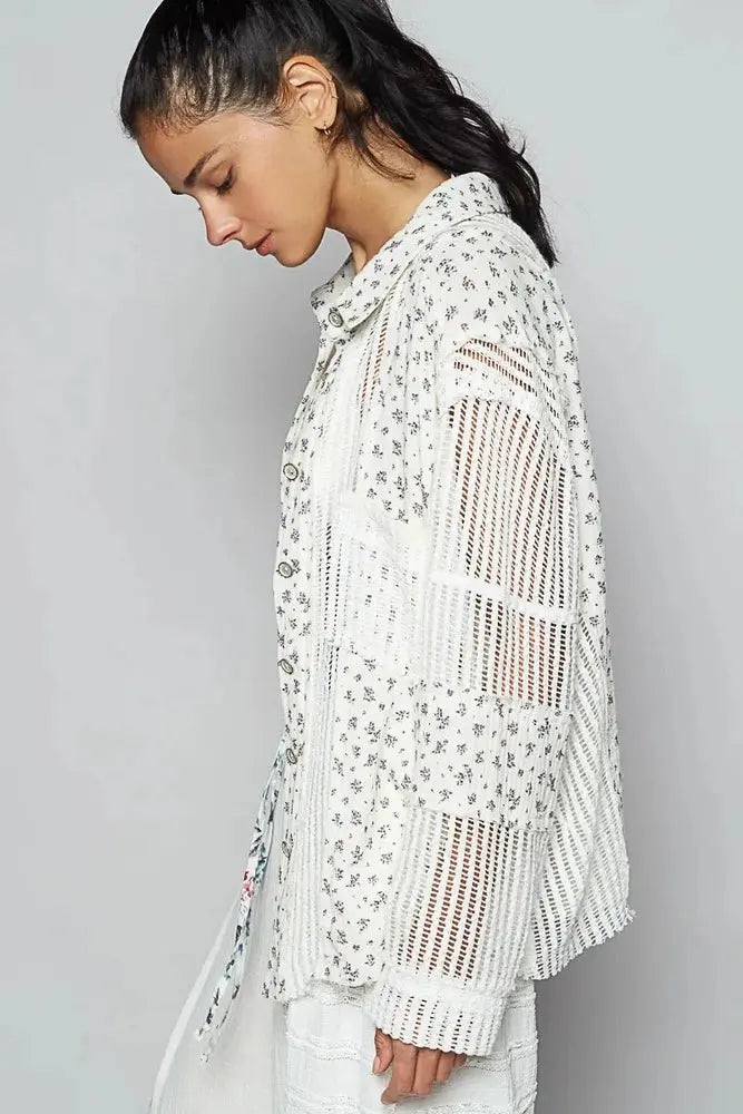 Woman wearing a white crochet top with floral patterns on a gray background