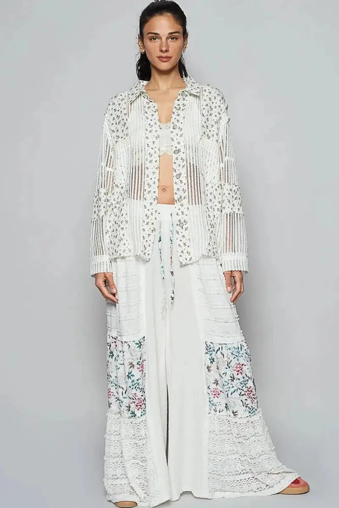 Woman wearing a white crochet top with floral patterns on a gray background