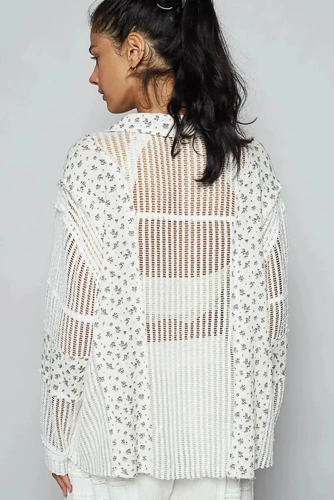 Woman wearing a white crochet top with floral patterns on a gray background