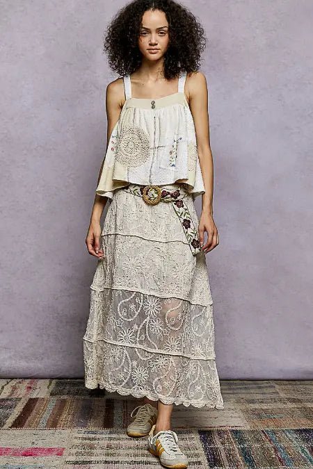Woman wearing a layered dress with floral patterns against a plain background