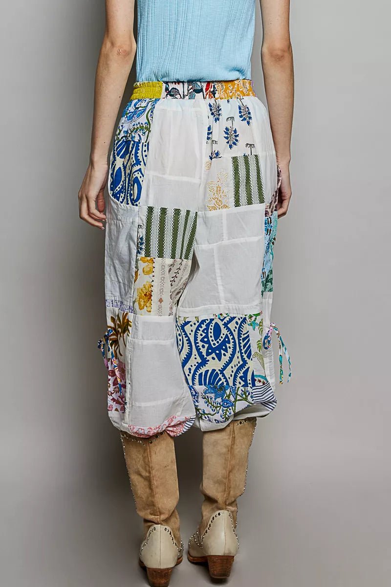 Person wearing a colorful patchwork skirt with a plain background