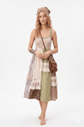 Woman wearing a patchwork dress with a brown bag on a white background